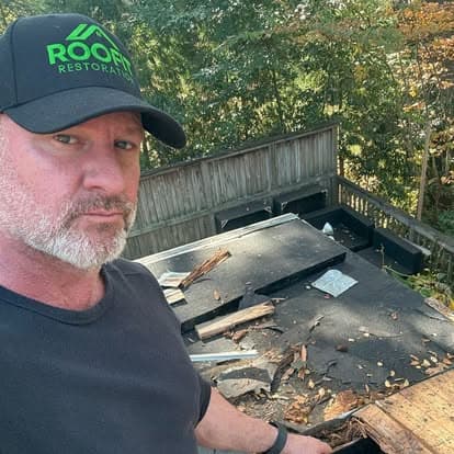 Roof inspector assessing damage on a residential roof surrounded by autumn foliage.
