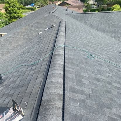 Overhead view of a newly installed gray shingle roof with a hose on top.